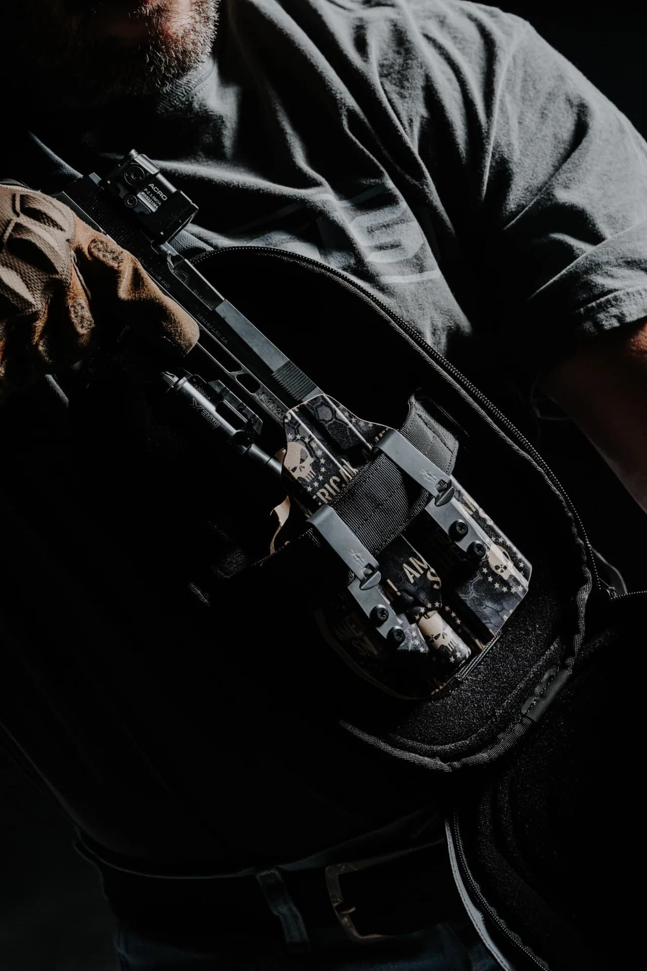 A holstered SIG Sauer pistol in an American Sniper design inside an open sling bag.
