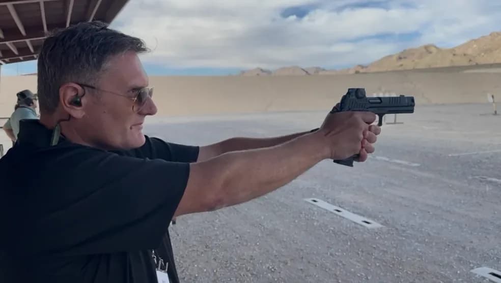 Wayne Lording taking aim with a pistol at an outdoor range.