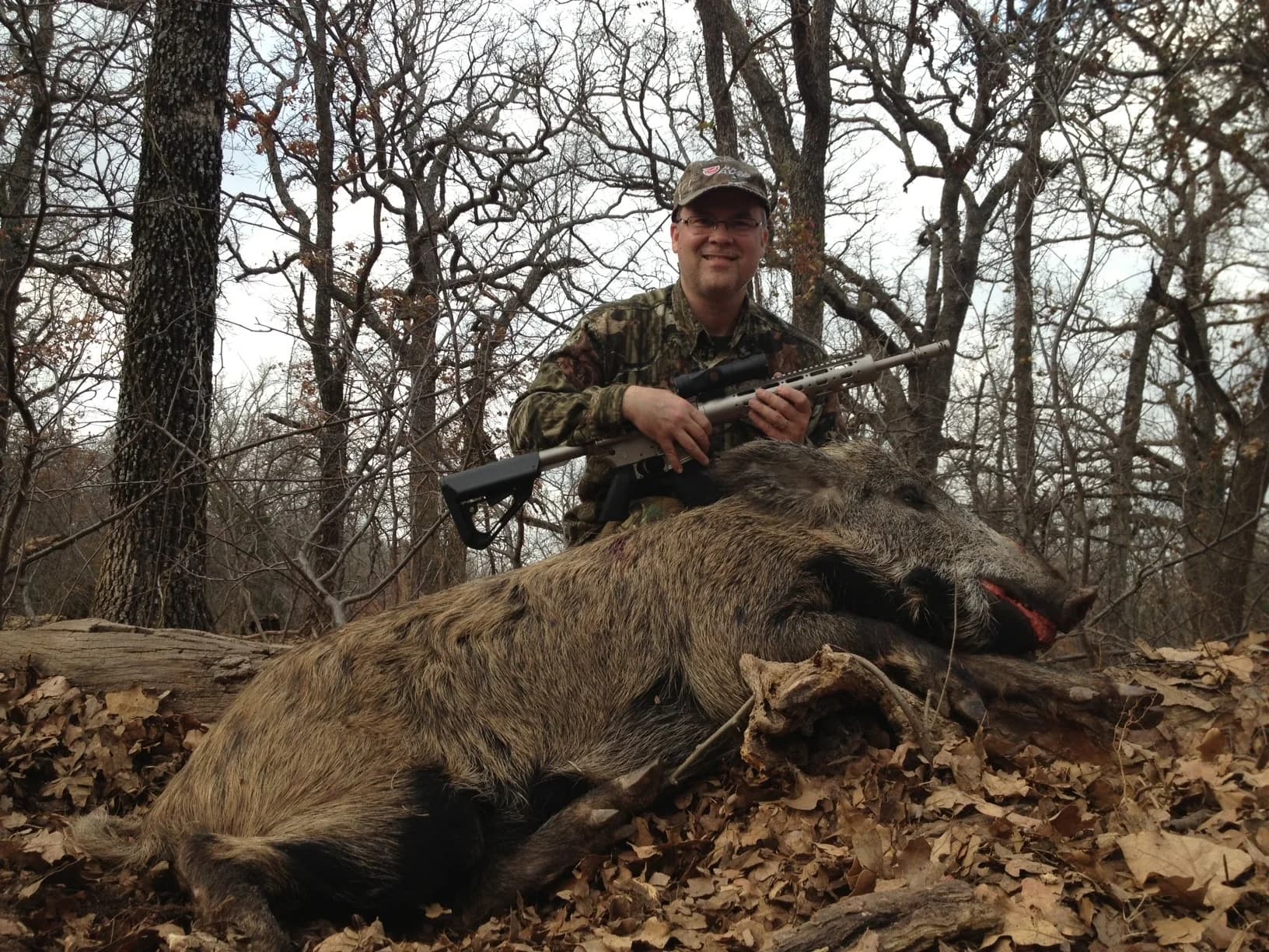 A hunter with a WMD Guns rifle and a wild boar in timber country.